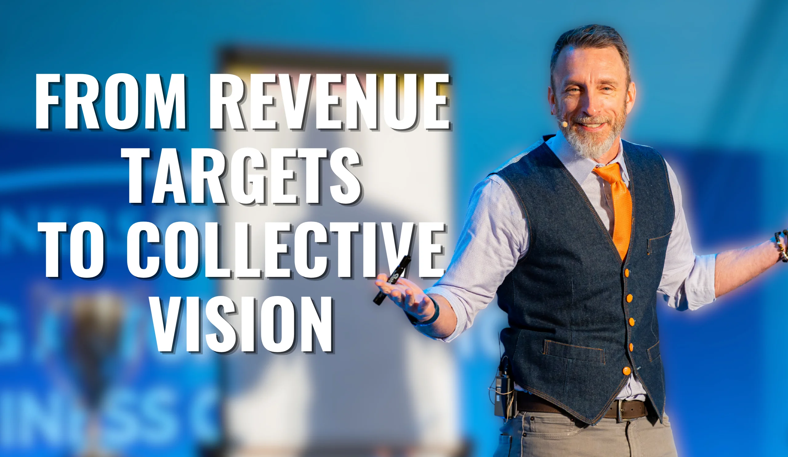 Smiling man in a vest presenting energetically on stage next to a flip chart with text ‘From Revenue Targets to Collective Vision,’ illustrating a motivational business talk about aligning teams around a shared vision rather than just hitting revenue goals.